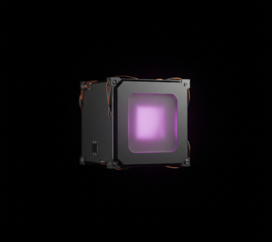 Close-up of a small cube-shaped satellite module against black space, its front face glowing violet-pink to evoke a tritium-powered energy source